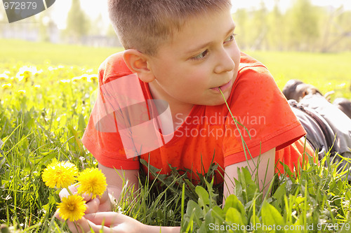 Image of Kid on grass with dandelions looking sideways