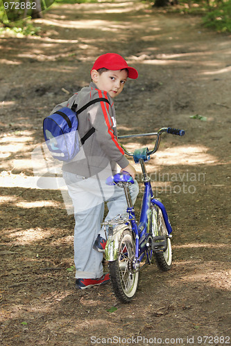 Image of Boy with bicycle glancing back