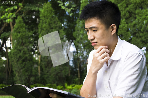 Image of young student reading books at the school park