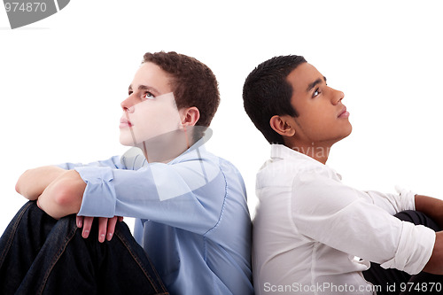 Image of two young man of different colors, sitting on floor, back to back