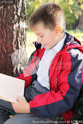 Image of Kid reading book in park sideview