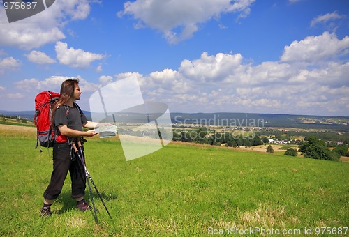 Image of Tourist with backpack, map and trekking sticks