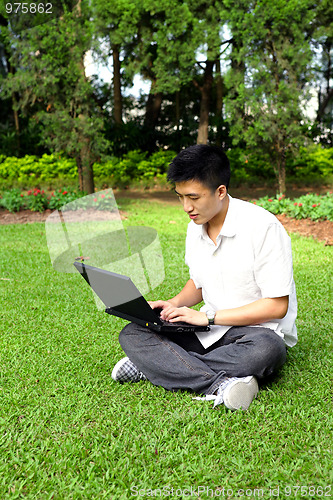 Image of asian man using computer outdoor 