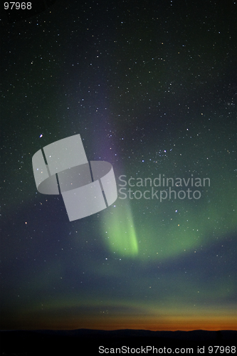 Image of Green-purple streak of aurora over twilight horizon. Many stars