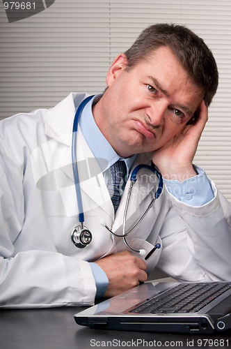 Image of Bored doctor sits at laptop