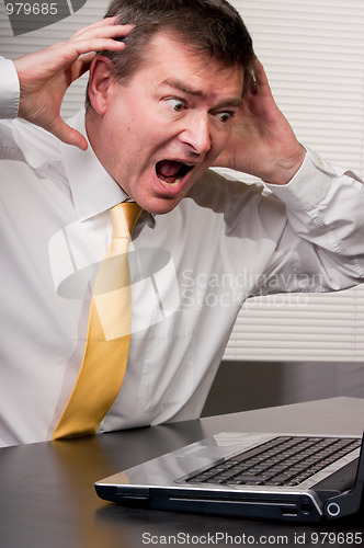 Image of Shocked business man raises hands to head