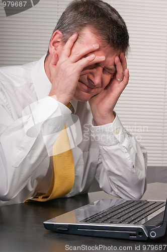 Image of Anxious business man holds head to reduce headache