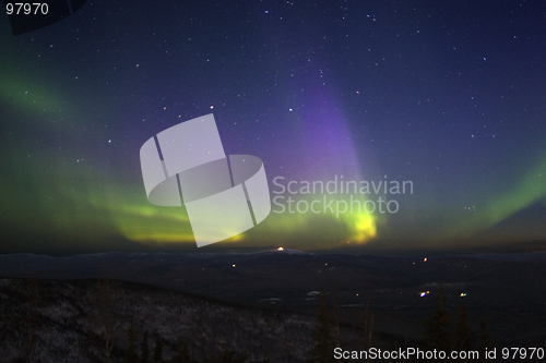 Image of Purple-green-yellowish northern lights in starry sky over hill t