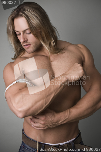 Image of A bodybuilder measuring the increase in his bicep