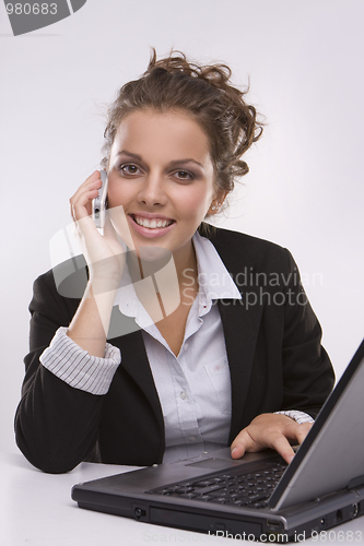 Image of woman using a laptop computer and talking on the phone