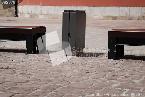 Image of Two stone benches and trash