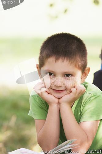 Image of Little smiling boy with book in park