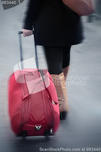 Image of women walking, pulling suitcase, blurred motion