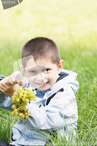 Image of Cute boy with heavy bunch of grapes