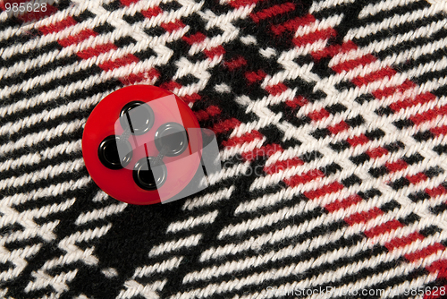 Image of Red button on checked fabric