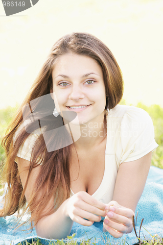 Image of Smiling brunette laying down on blue towel
