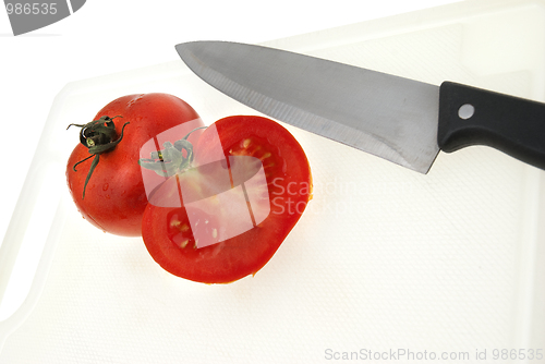 Image of Cutting white plastic board with a knife and tomato