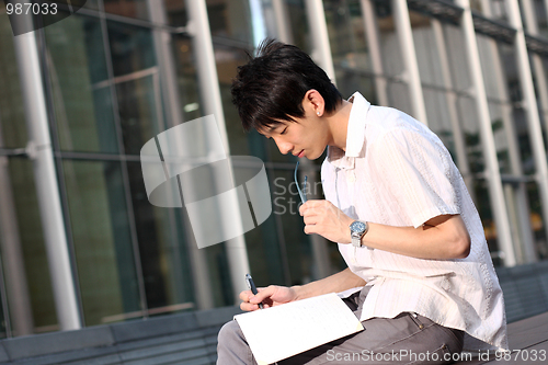 Image of casual asian businessman texting on his book