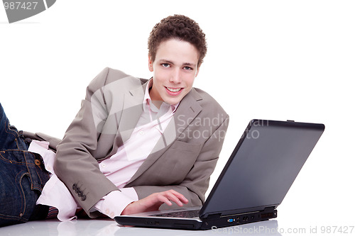 Image of Young man smiling and typing on laptop
