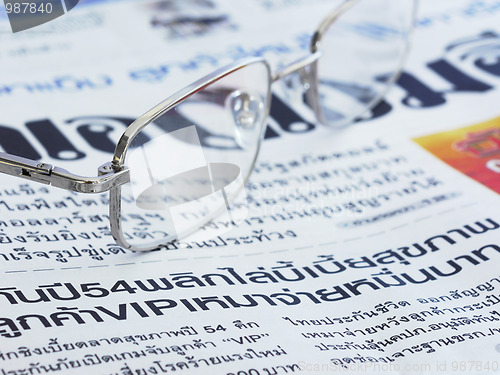 Image of Close-up of Thai language newspaper and a pair of glasses