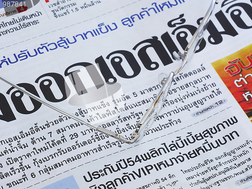 Image of Close-up of Thai language newspaper and a pair of glasses.