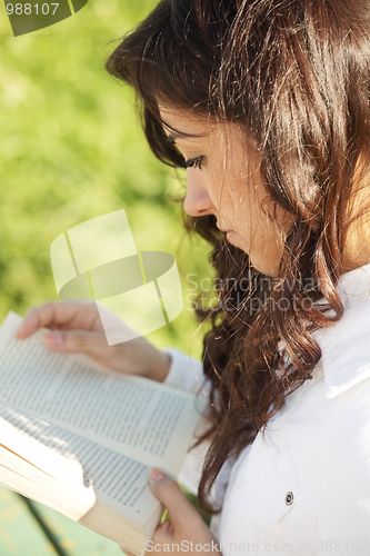 Image of Young brunette in white reading book sideview