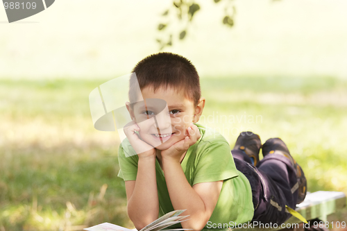 Image of Little smiling kid with book in park