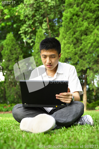 Image of asian man using computer outdoor