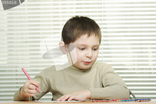 Image of Cute boy at desk with crayons