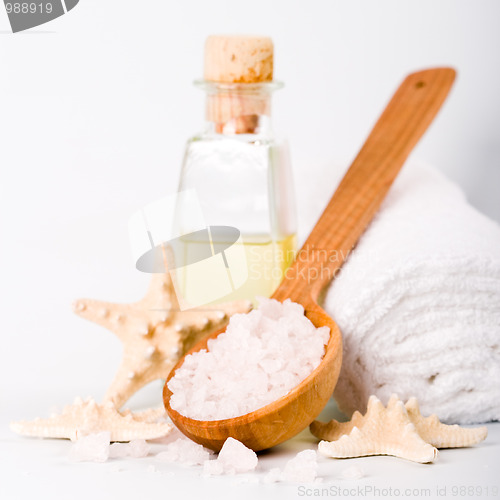 Image of sea salt on wooden spoon, towel, oil and stars