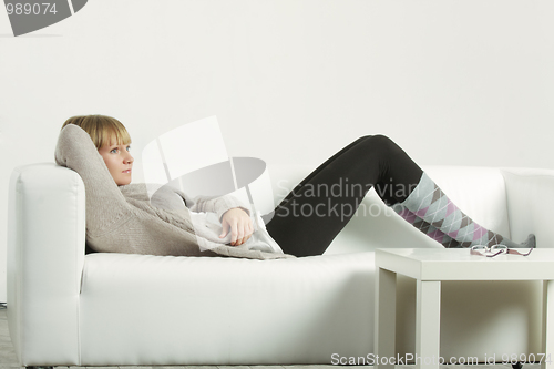 Image of Woman in cardigan relaxed on sofa