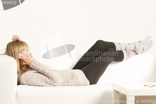 Image of Woman with cellphone laying on sofa