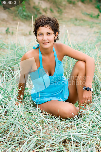 Image of woman in blue sitting in a grass