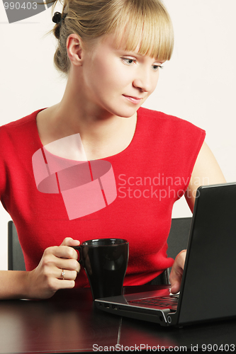 Image of Blonde businesswoman in red working on laptop