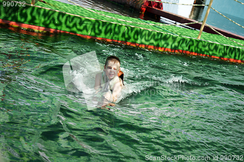 Image of Squinting boy swimming with dolphin