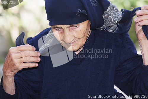 Image of Senior woman ties up head with scarf