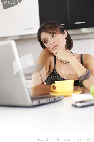 Image of Modern woman reading e-mails at her breakfast