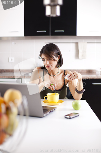 Image of Modern woman reading e-mails at her breakfast