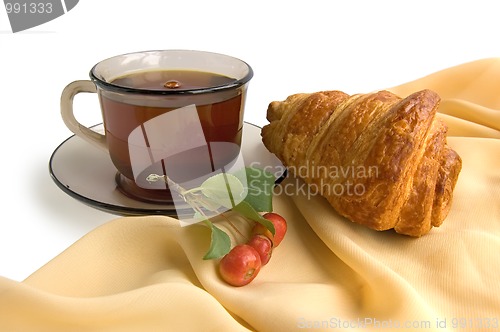 Image of Brown glass cup with tea and croissants