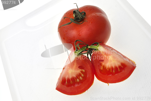 Image of Cutting white plastic board with red tomato