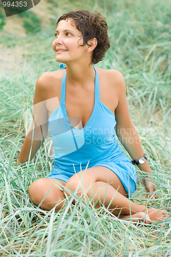 Image of brunet woman in blue sitting in a grass