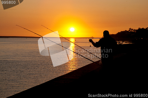 Image of Man fishing on sunset 