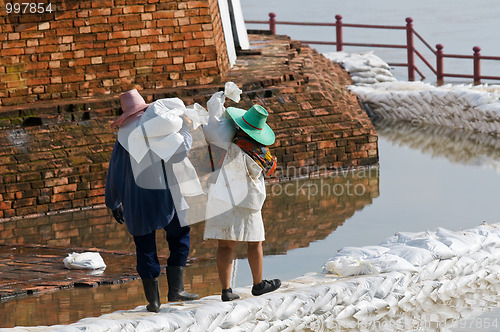 Image of Women carrying sandbags during flood in Thailand