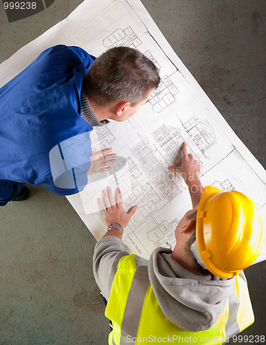 Image of Builders examine blueprints