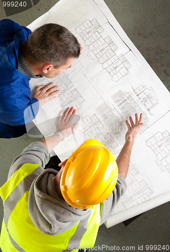 Image of Builders examine blueprints