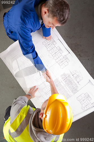 Image of Builders shake hands over blueprint