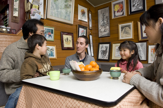 A student enjoys talking to his Japanese host family. 