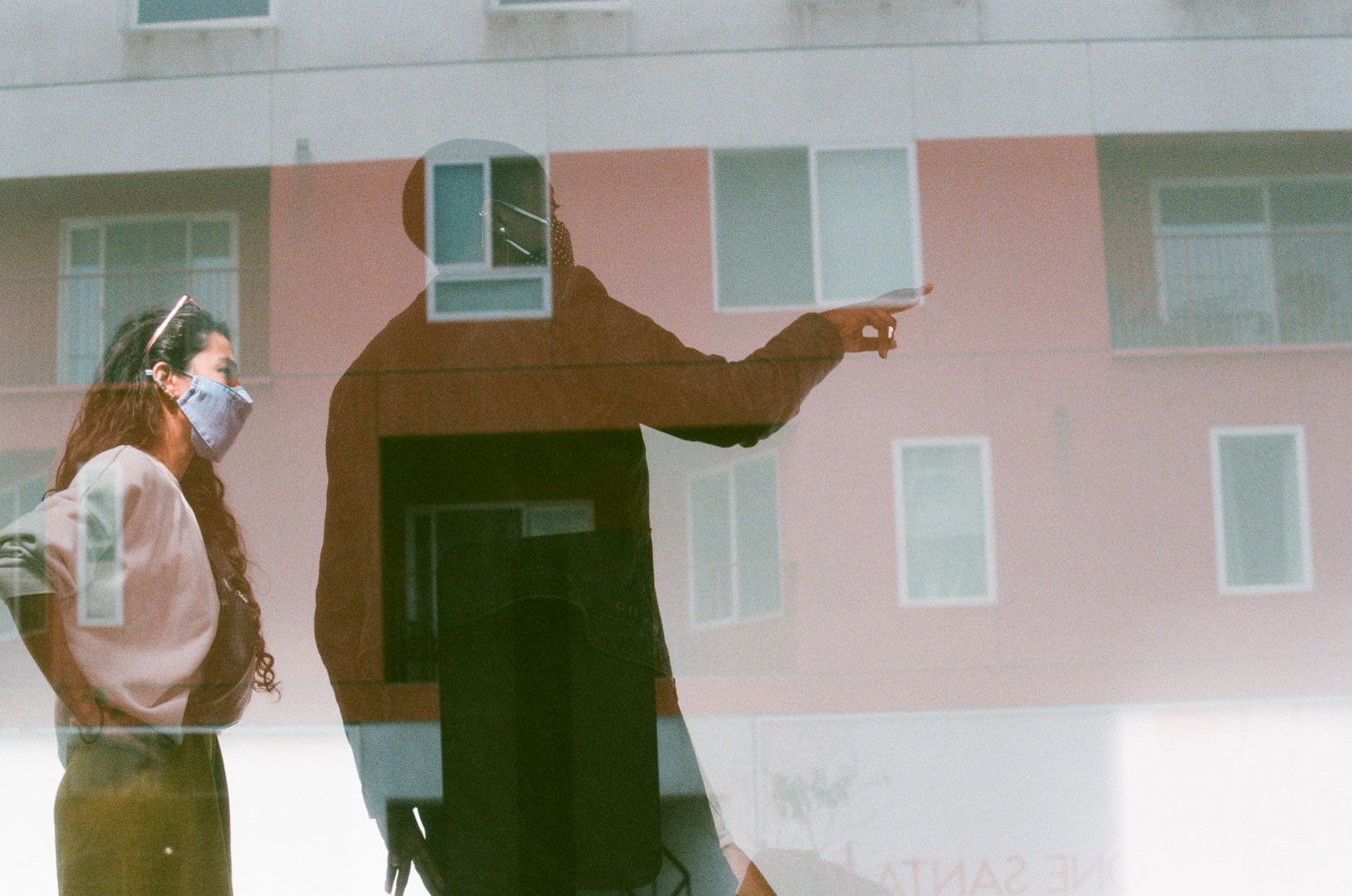 two women with masks pointing window reflection