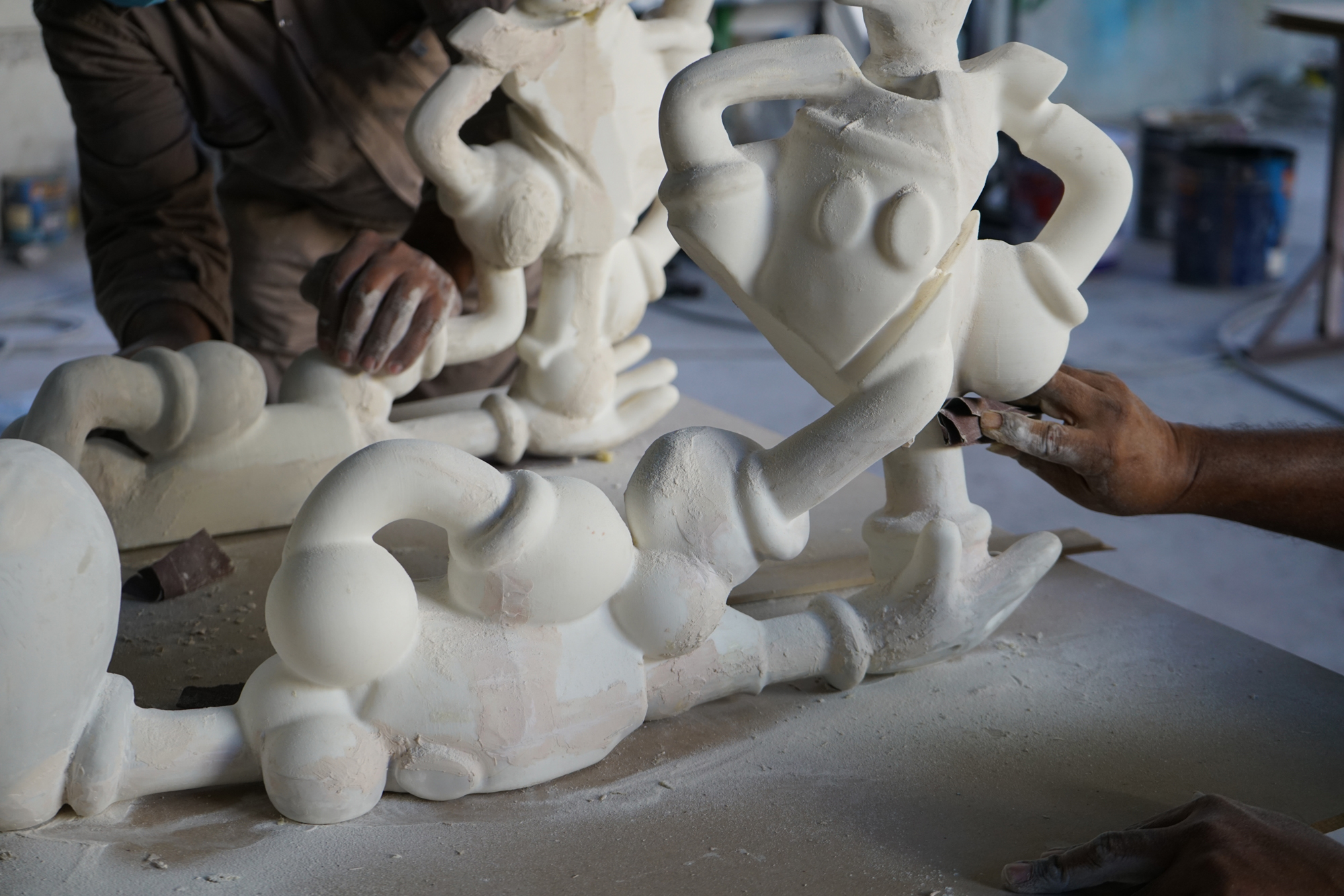 hands sanding white plaster sculpture