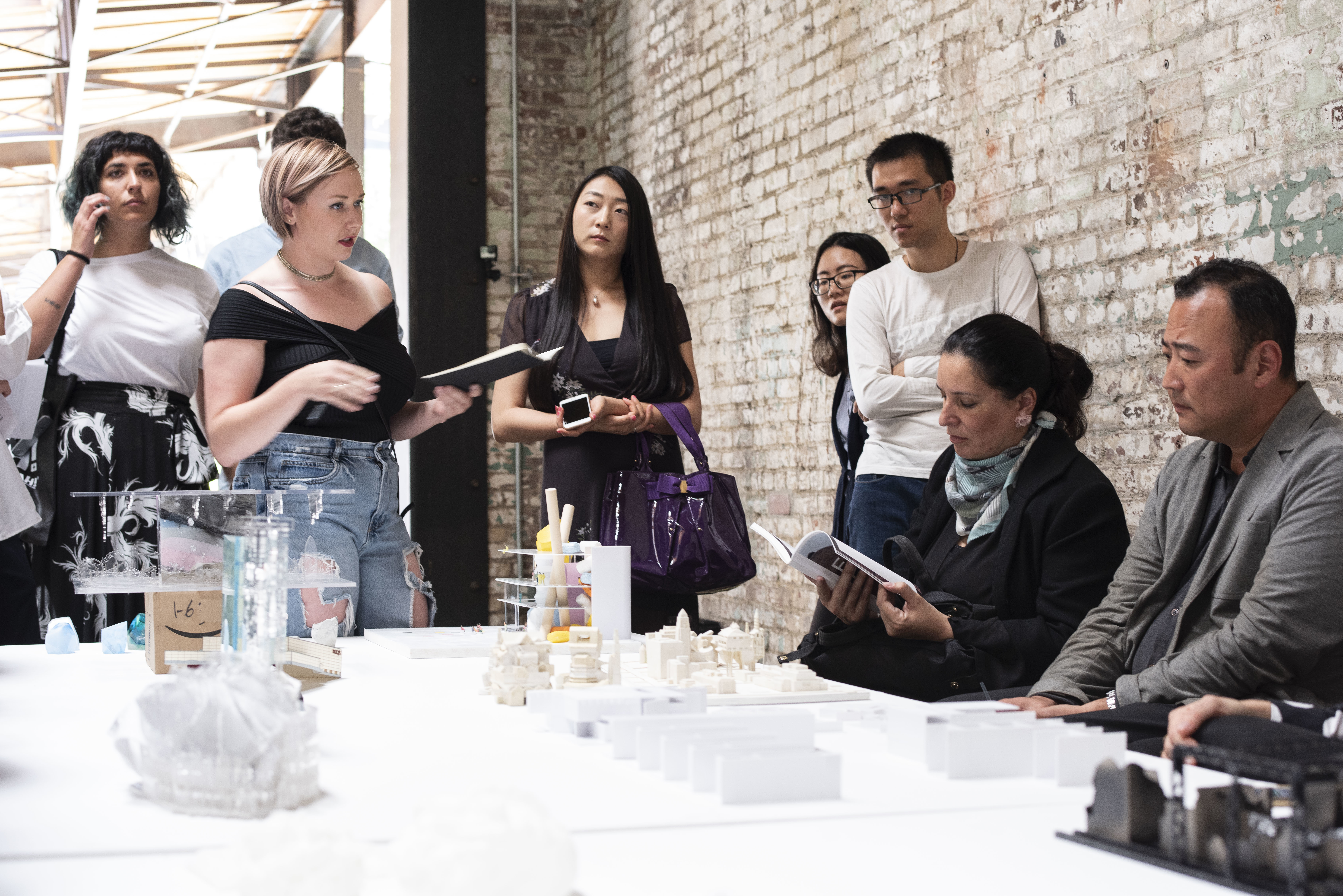 student presenting miniature thesis model brick corridor gallery